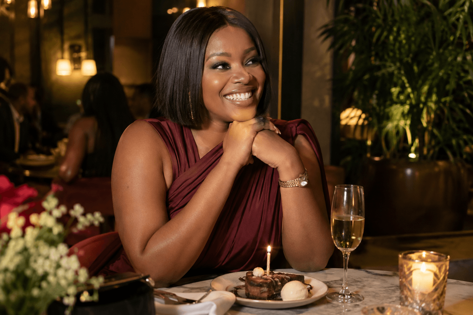 A Nigerian woman dressed for her solo birthday dinner, holding a small cake.